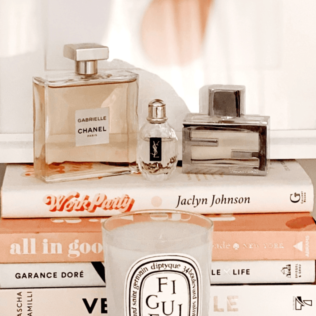 A stylish arrangement of luxury perfumes, designer books, and a scented candle, symbolizing high-end branding, fashion marketing, and luxury retail strategy.