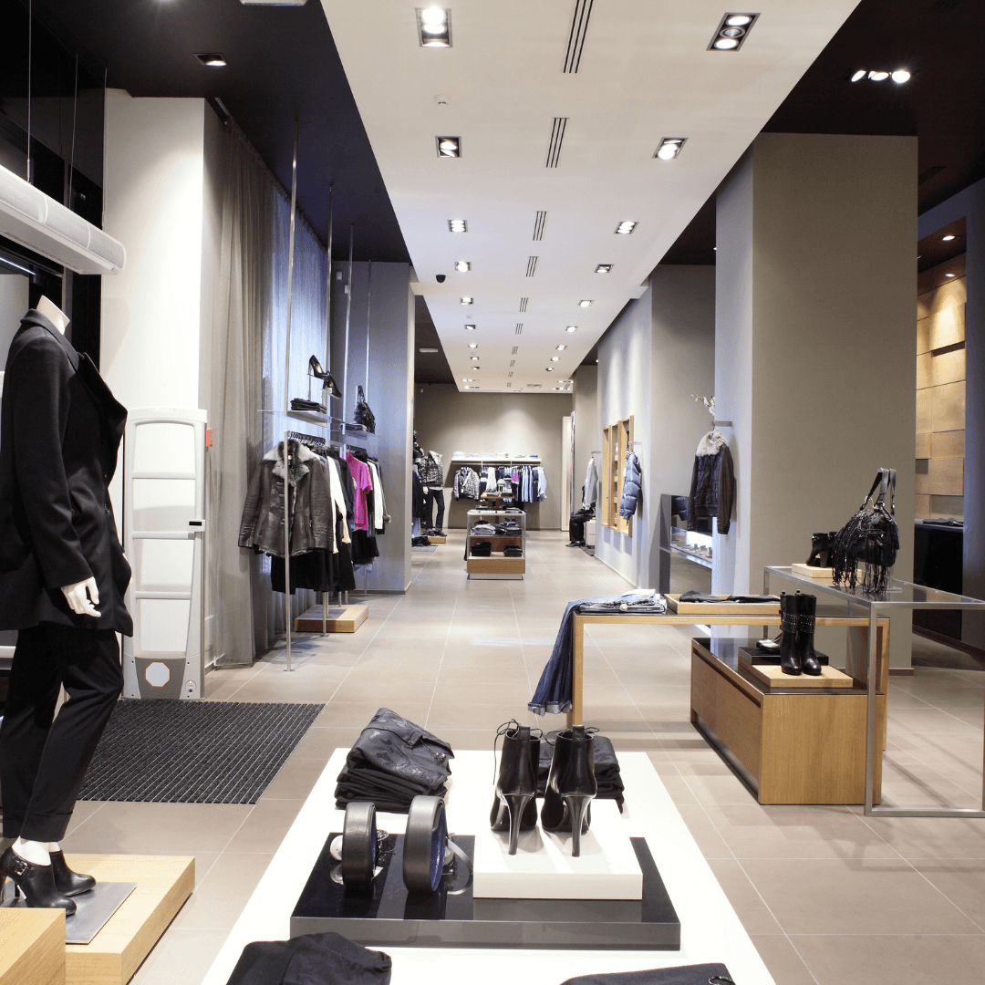 Modern retail store with stylish visual merchandising, featuring mannequins, apparel displays, and accessories in a well-lit space.