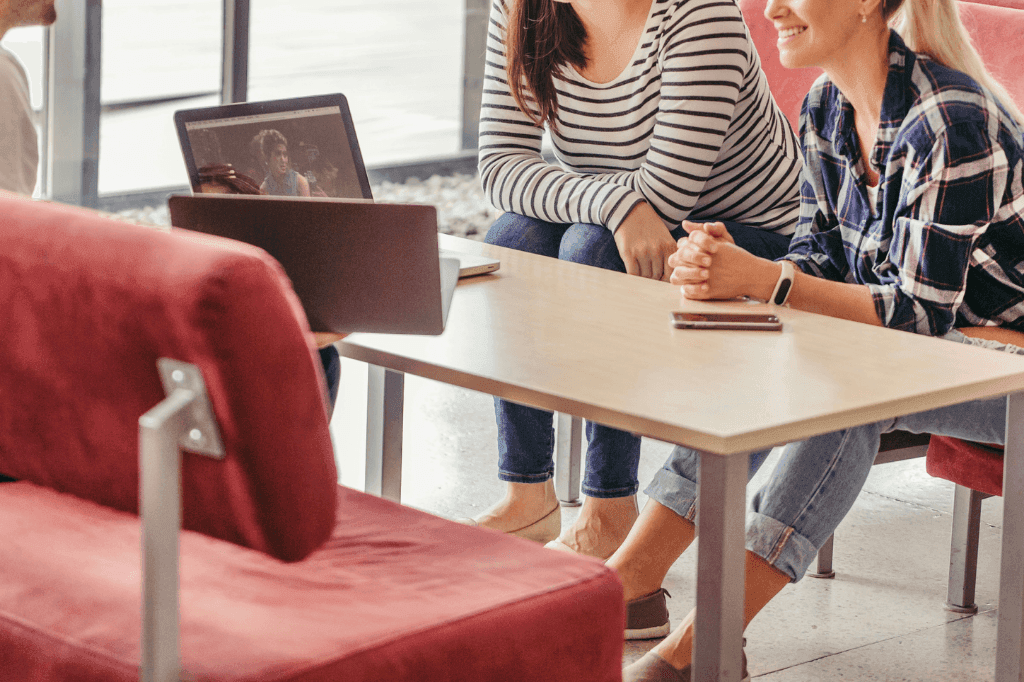 Two women having a business strategy meeting with a laptop in a casual office setting